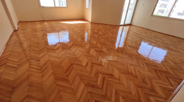 Plancher en bois massif avec lames de parquet disposées en quinconce, présentant des variations naturelles de teintes allant du brun clair au brun foncé